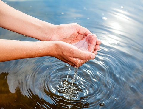 Imagen de manos recogiendo agua limpia desde una corriente  de agua